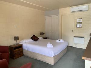 Robertson Country Motel في روبرتسون: غرفة نوم بسرير ابيض كبير وكرسي
