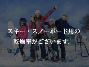um grupo de pessoas posando para uma foto na neve em Minshuku Kojima em Nozawa Onsen