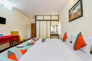 een slaapkamer met een groot wit bed met kleurrijke kussens bij FabExpress Wenlock Homes in Ooty