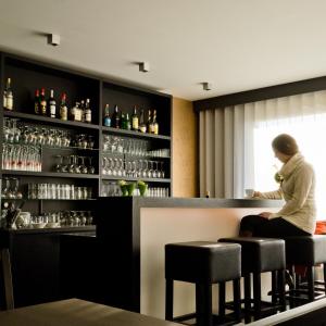 una mujer sentada en un bar en un restaurante en Hotel Essenza, en Puurs