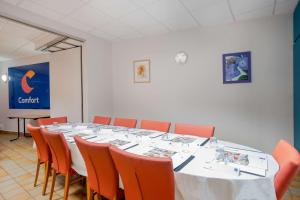 una sala de conferencias con una mesa larga y sillas naranjas en Comfort Hotel Montlucon en Montluçon