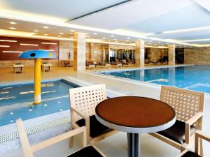 a swimming pool with a table and chairs in front of it at Pullman Linyi Lushang in Linyi