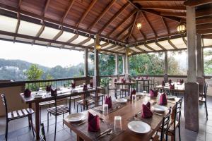 a restaurant with wooden tables and chairs and a balcony at Piumara Residence in Kandy