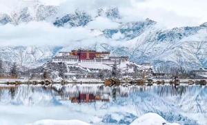a snow covered mountain with a building on a lake at Honey Bee Hub in Lhasa