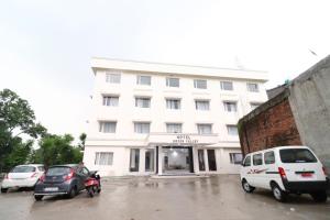 a white building with cars parked in front of it at Hotel Green Valley in Katra