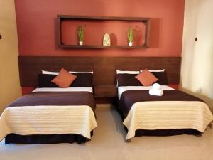 Villa San Antonio de Padua في إسامال: سريرين في غرفة بجدران حمراء