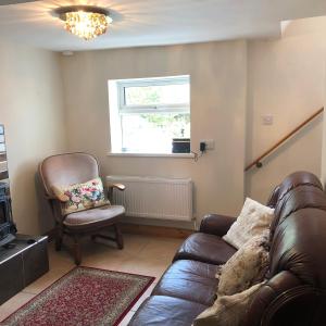 sala de estar con sofá de cuero y silla en NEW LISTING Faye’s Place, en Donegal