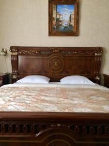 ヴォルゴグラードにあるGostevoi Dom Imperiaの木製ベッド1台付きのベッドルーム1室(壁に絵画付)