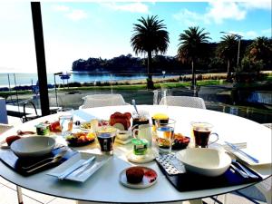 una mesa blanca con comida y bebidas encima en Waters Edge B&B, en Whitianga