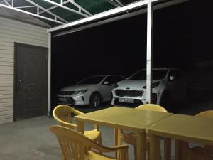 twee auto's geparkeerd in een garage met een tafel en stoelen bij Capsule Hostel in Karakol