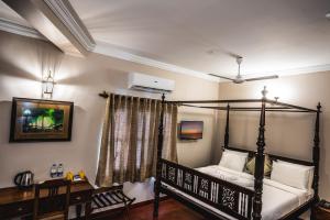 a bedroom with a four poster bed and a desk at 19VillaMira in Pondicherry