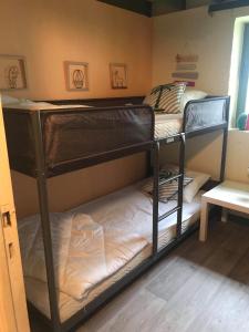 two bunk beds in a room with a table at Loft rénové au calme à la campagne pour famille in Hastière-par-delà