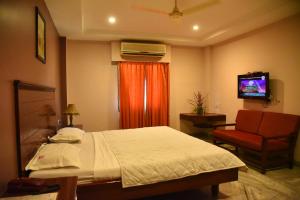 Hotel Subhalakshmi Palace في كارايكودي: غرفة نوم بسرير وكرسي وتلفزيون