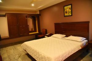 1 dormitorio con 1 cama grande y cabecero de madera en Hotel Subhalakshmi Palace, en Kāraikkudi