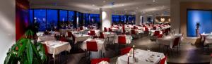 un restaurante con mesas blancas y sillas rojas en Rimske Terme Resort - Hotel Zdraviliški dvor, en Rimske Toplice