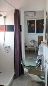 ein Badezimmer mit einem Glaswaschbecken und einer Dusche in der Unterkunft Grande villa avec piscine et jacuzzi in Terre-de-Haut