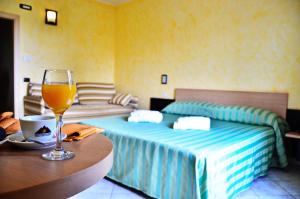ein Zimmer mit einem Bett und einem Glas Wein auf einem Tisch in der Unterkunft Hotel Onda Bleu in Botricello