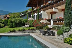 Casa con piscina y mesa con sombrilla en Egger Apartments, en Rifiano