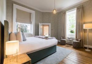 a bedroom with a large bed and two windows at Pelham House in Lewes