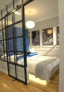 - une chambre avec un lit et une paroi en verre dans l'établissement Blue Velvet Premium Apartments, à Toruń