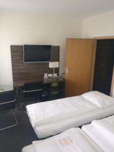 a hotel room with two beds and a desk and a television at Behringers City Hotel Nürnberg in Nürnberg