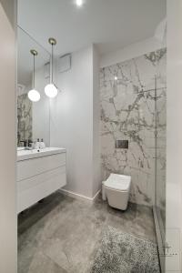 a bathroom with a white toilet and a sink at Apartament DeLux in Poznań