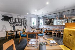 a restaurant with wooden tables and chairs and a cow on the wall at Inn on the Square in Keswick