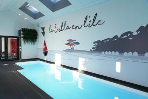 a swimming pool in a building with a sign that reads inclusive at La Villa en L'île - 2 Piscines & Spa in Noirmoutier-en-l'lle