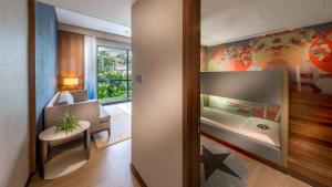 a room with a bedroom with a bed and a chair at Hard Rock Hotel Desaru Coast in Desaru