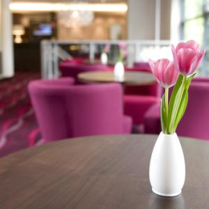 un jarrón blanco con flores rosas sentado en una mesa en Manchester South Hotel, Sure Hotel Collection by BW, en Mánchester