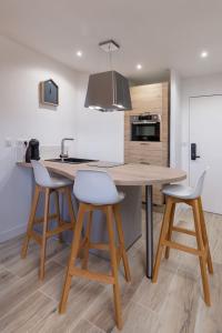 a kitchen with a wooden table and two bar stools at Superbe Appartement - 3km DisneyLand et 20 min des JO in Magny-le-Hongre