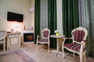 a living room with two chairs and a table and a television at Hotel Royal Craiova in Craiova