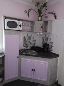 a small kitchen with a sink and a microwave at Levendula Apartman in Makó