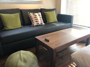 Condominium MIRAHAKONE في هاكوني: أريكة زرقاء مع وسائد وطاولة قهوة خشبية