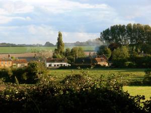 a green field with houses and trees in the distance at 3 Corners B&B in Holt
