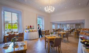 a man standing in a restaurant with tables and chairs at Boyne Valley Hotel - Bed & Breakfast Only in Drogheda