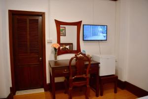 a room with a desk with a television and a chair at Thatsaphone Hotel in Luang Prabang