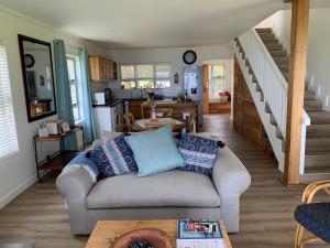 a living room with a couch and a kitchen at Trinity Farm Ocean view Cottage in Plettenberg Bay
