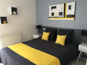 een slaapkamer met een bed met gele lakens en kussens bij ZIBURU TERRASSE PARKING TOUT A PIED SAINT JEAN DE LUz in Ciboure