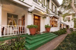 a white house with green steps and potted plants at Royston Hall Historical Guesthouse in Umtentweni