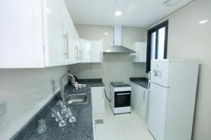 a white kitchen with a sink and a refrigerator at ماجيك سويت صباح السالم Magic suite sabah Alsalem in Kuwait