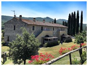 a large stone house with a fence and flowers at Agriturismo Due Ponti in Chianni