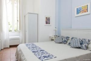 a white bedroom with a bed with blue and white pillows at Il Miraggio in Fregene