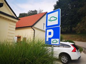 un coche aparcado junto a una señal de estacionamiento con una señal de cerdo en Villa Istenič, en Bizeljsko