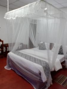 um quarto com uma cama de dossel e cortinas brancas em Samiru Guest Inn Ella em Ella