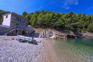 a boat on a rocky beach next to a building at Robinson Tabinja in Sućuraj