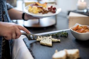 a person cutting up some food on a cutting board at KOMPAS Hotel Aalborg in Aalborg