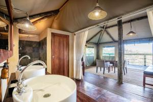 a bathroom with a sink and a dining room at Eagle Tented Lodge & Spa in Okaukuejo