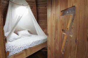 エピニアックにあるInsolite dans les arbres Les Ormes, Epiniacのカーテン付きの木造の部屋のベッド1台