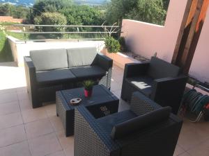 un patio con 2 sedie, un divano e un tavolo di Villa A Schiera Porto Pozzo a Porto Pozzo